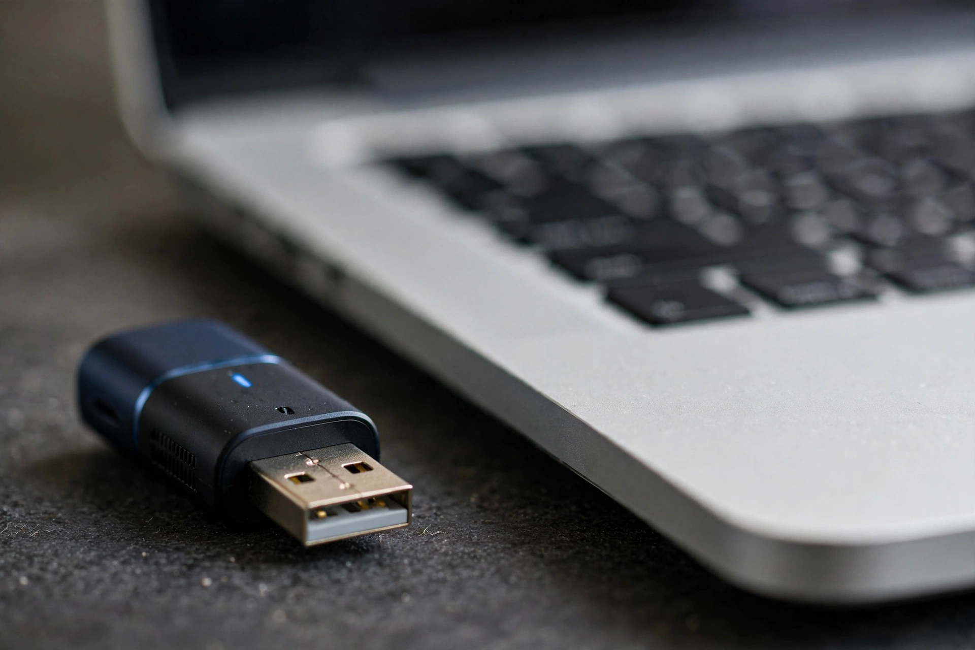 USB Bluetooth adapter next to a laptop for upgrading PC Bluetooth